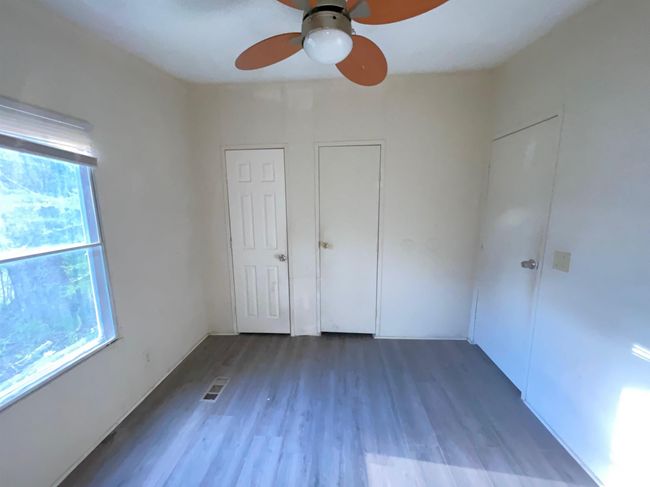 Empty room with wood finished floors, a ceiling fan, and visible vents | Image 9