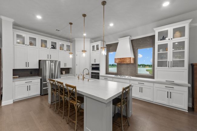 Remodeled kitchen with appliances with stainless steel finishes, a sink, stately wood flooring, tasteful backsplash, and custom vent-a-hood | Image 13