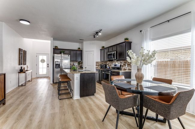 Kitchen featuring appliances with stainless steel finishes, tasteful backsplash, a center island with sink, light wood-type flooring, and a kitchen bar | Image 15