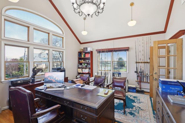 Office featuring crown molding, wood finished floors, high vaulted ceiling, and a baseboard radiator | Image 39