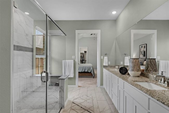Bathroom with ensuite bathroom, marble look tile flooring, double vanity, a shower stall, and baseboards | Image 15