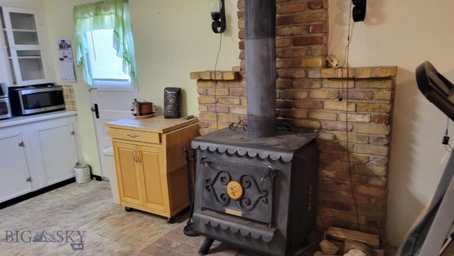 Kitchen featuring white cabinets and a wood stove | Image 8