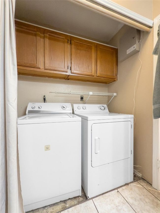 Laundry area with washer and clothes dryer, cabinet space, and light tile patterned flooring | Image 17