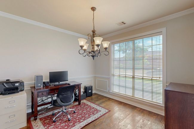 Home office with wood finished floors, a chandelier, a wainscoted wall, ornamental molding, and visible vents | Image 13