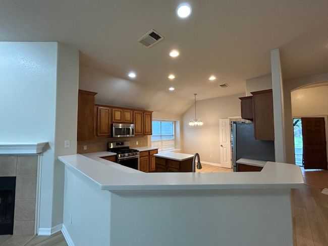 Kitchen featuring stainless steel appliances, a kitchen island, light countertops, recessed lighting, and arched walkways | Image 4