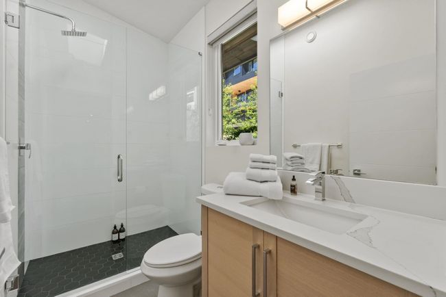 Bathroom featuring toilet, vanity, and a stall shower | Image 16