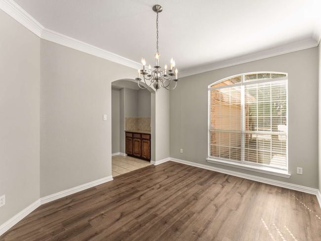 Unfurnished room with a notable chandelier, wood finished floors, arched walkways, and ornamental molding | Image 23