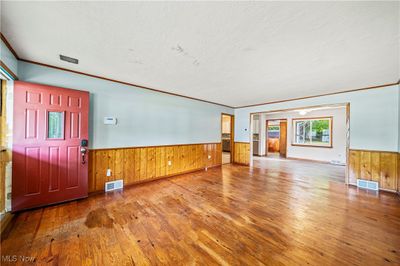 Entrance foyer featuring hardwood / wood-style flooring, wooden walls, ornamental molding, and a textured ceiling | Image 3