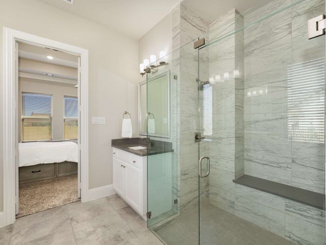 Primary spa-like bathroom with dual quartz-topped vanities, a freestanding soaking tub, and an oversized frameless shower with bench | Image 16