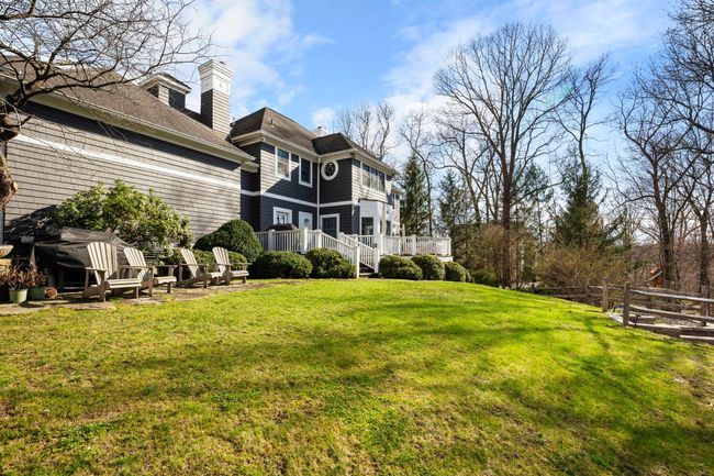 The rear of the home features a stunning façade with multiple walk-outs to a spacious deck that overlooks a lush, gently sloping yard—perfect for outdoor entertaining or play. | Image 42