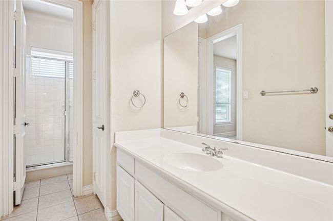 Full bath with healthy amount of natural light, vanity, tile patterned floors, and an enclosed shower | Image 32
