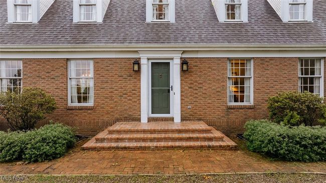 Doorway to property featuring roof with shingles and brick siding | Image 4