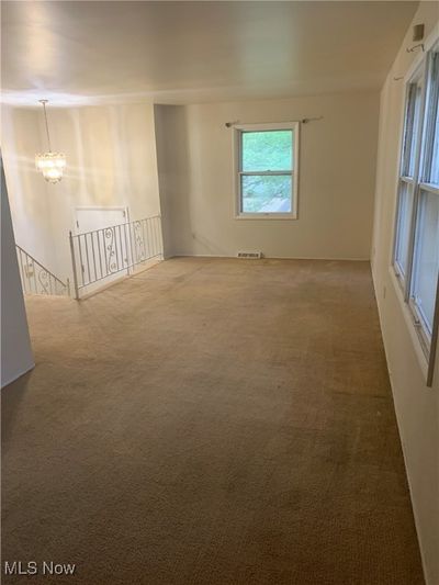 Carpeted empty room with an inviting chandelier | Image 3