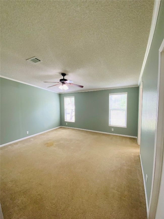 Spare room featuring visible vents, crown molding, baseboards, light colored carpet, and ceiling fan | Image 18
