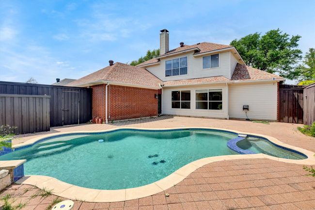 View of swimming pool with a patio area, a pool with connected hot tub, and a fenced backyard | Image 4