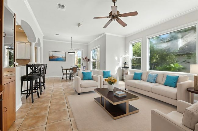 Living area with healthy amount of natural light, light tile patterned floors, ornamental molding, and ceiling fan | Image 17