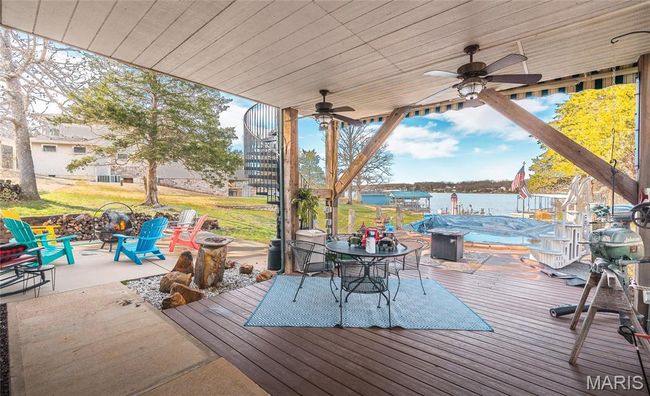 Covered Deck/Patio off Pool with an outdoor fire pit, outdoor dining area, a water view, ceiling fan. | Image 40