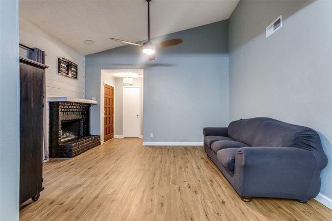 Sitting room featuring vaulted ceiling, a brick fireplace, wood finished floors, and a ceiling fan | Image 4