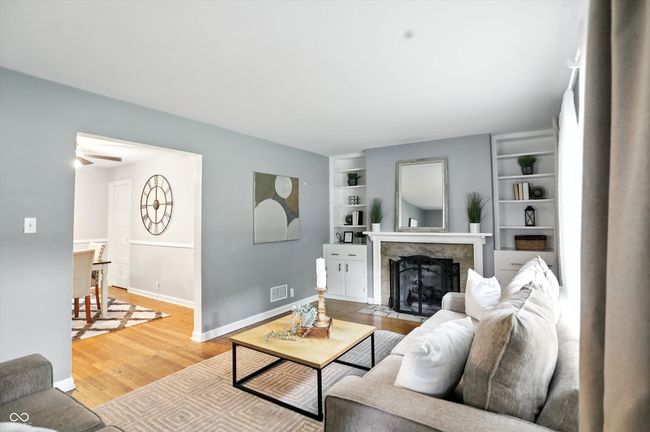living area with wood finished floors, a tiled fireplace, and built in shelves | Image 14