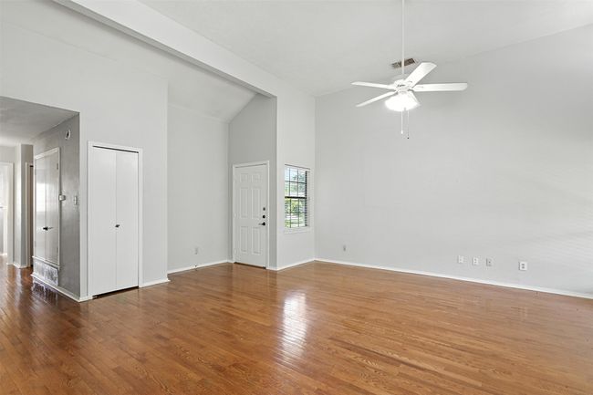 Unfurnished living room featuring a ceiling fan, high vaulted ceiling, and wood finished floors | Image 9