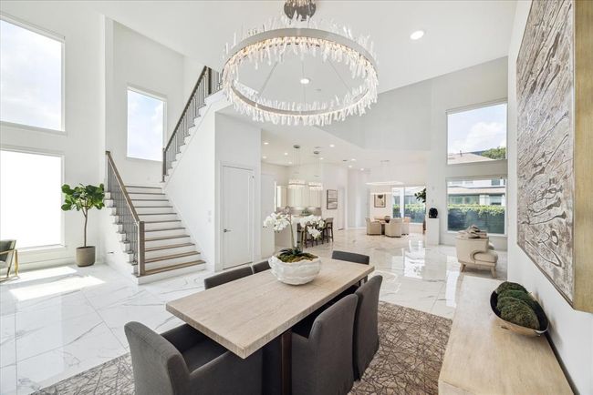 The centerpiece of this exquisite space is a stunning crystal chandelier that casts a dazzling array of light, creating a warm and inviting atmosphere for dining and entertaining. The room features clean lines and an open layout, seamlessly connecting with the rest of the home while providing an intimate setting for meals. | Image 7
