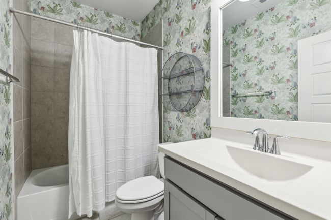 Bathroom with wallpapered walls, toilet, shower / bathtub combination with curtain, and vanity | Image 21