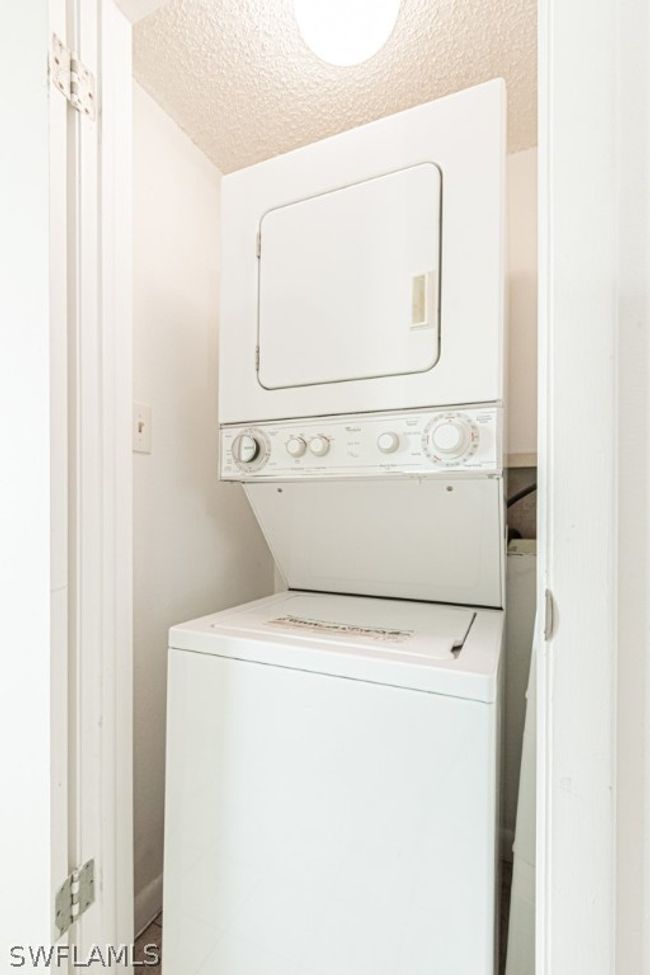 Laundry area featuring stacked washing maching and dryer and a textured ceiling | Image 24