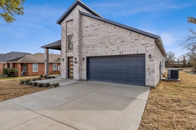 View of front facade with brick siding, driveway, and an attached garage | Image 4