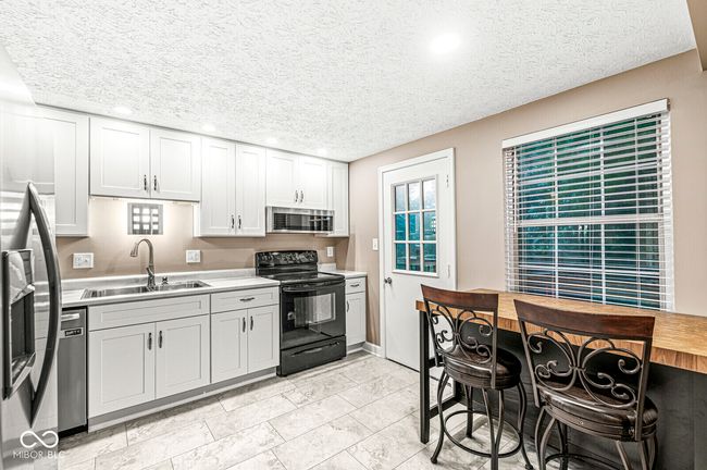 kitchen featuring appliances with stainless steel finishes, light countertops, recessed lighting, a textured ceiling, and white cabinets | Image 4