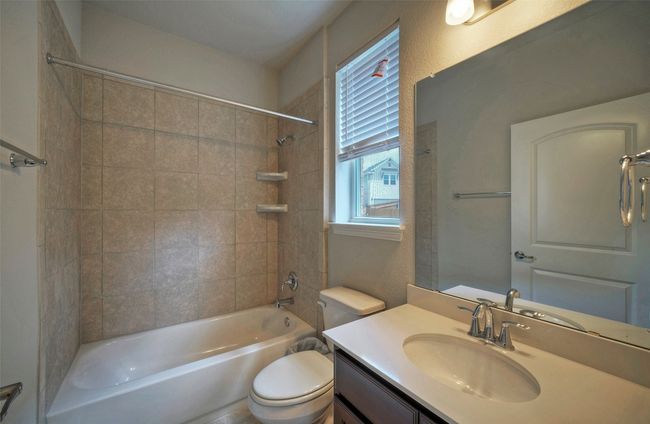 Full bath featuring toilet, vanity, a textured wall, and shower combination | Image 14