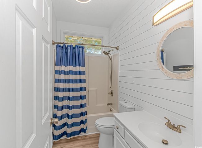 Full bathroom with toilet, wooden walls, shower / tub combo, wood finished floors, and vanity | Image 20