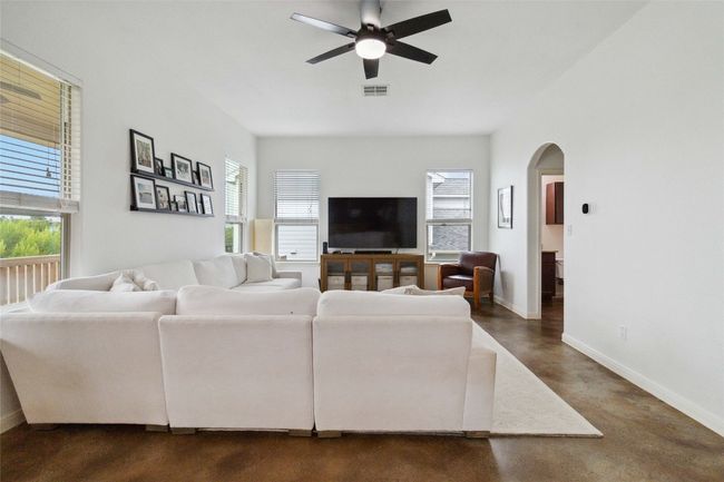 Living area with arched walkways, ceiling fan, baseboards, and concrete flooring | Image 7