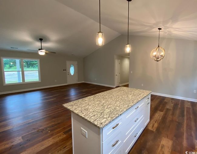 Kitchen featuring a ceiling fan, dark wood finished floors, lofted ceiling, white cabinetry, and a kitchen island | Image 4