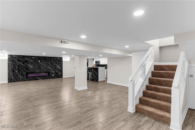 Unfurnished living room featuring wood finished floors, stairway, bar area, and recessed lighting | Image 27