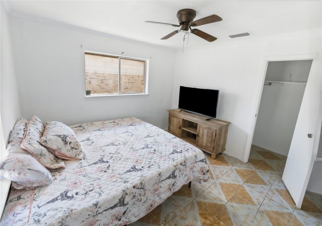 Bedroom with light tile patterned floors, crown molding, a closet, and ceiling fan | Image 10