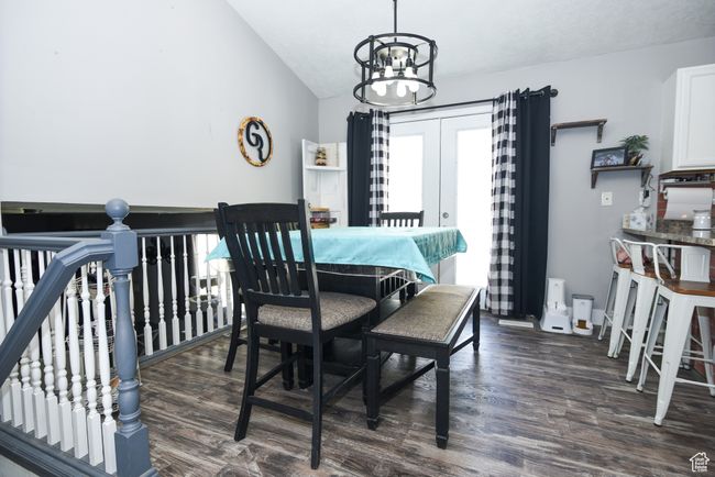 Dining space with dark wood finished floors, a chandelier, and vaulted ceiling | Image 12