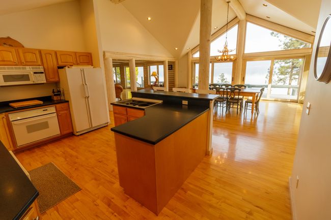 Kitchen featuring white appliances, high vaulted ceiling, light hardwood / wood-style flooring, and a center island | Image 23