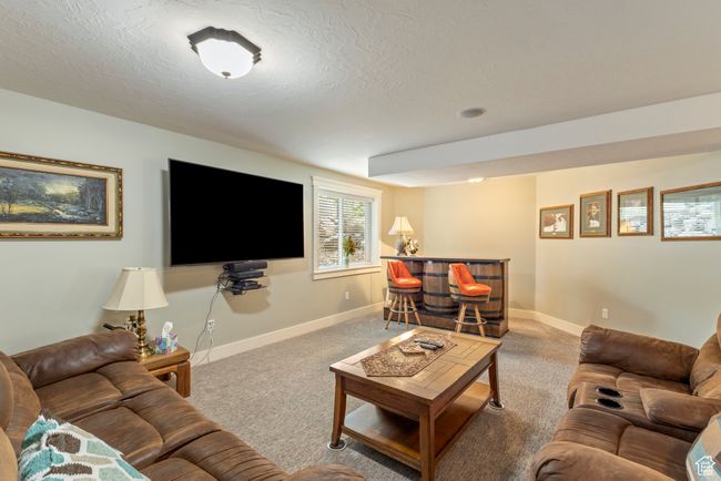 Carpeted living room with a dry bar, baseboards, and a textured ceiling | Image 24