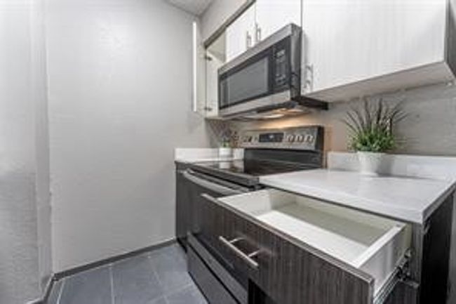Kitchen with appliances with stainless steel finishes, dark tile patterned flooring, and light countertops | Image 9