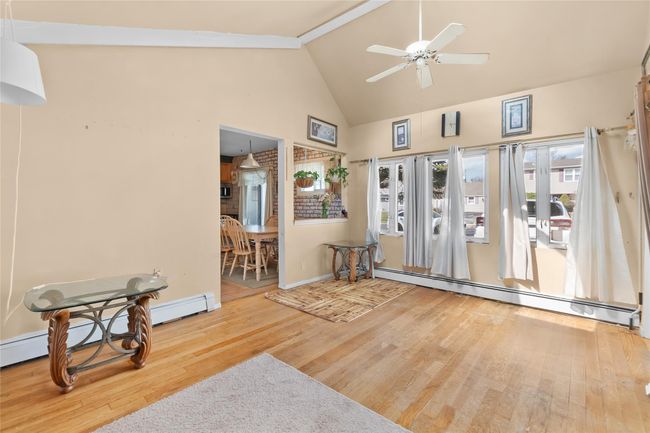 Entryway with high vaulted ceiling, wood finished floors, a baseboard radiator, baseboards, and ceiling fan | Image 9