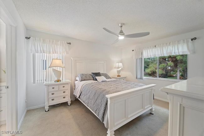 Bedroom with light carpet, a textured ceiling, baseboards, and ceiling fan | Image 4