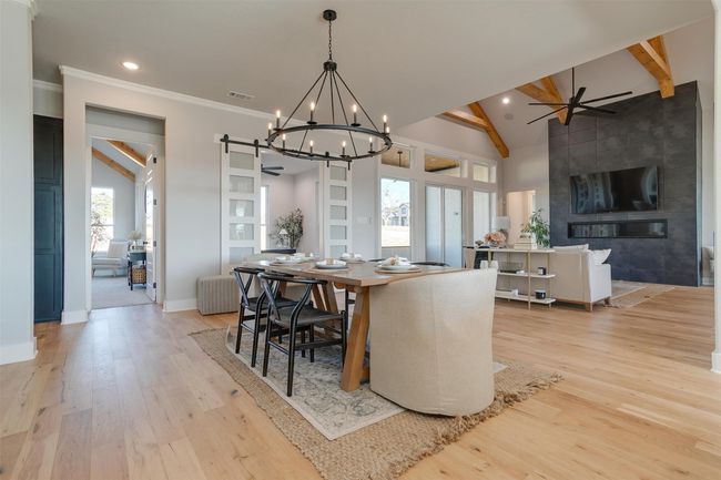 Dining area with beamed ceiling, ceiling fan with notable chandelier, light hardwood / wood-style floors, and high vaulted ceiling | Image 10