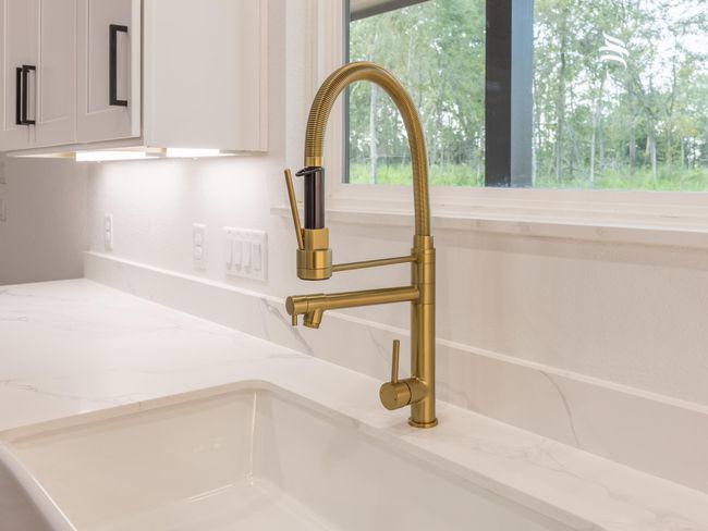 A closer look at the elegant brushed gold pull-down faucet and marble-inspired countertops—adding just the right amount of glam to your daily routine. | Image 16