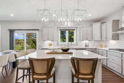 (*Photo of decorated model, actual homes colors and finishes will vary) The kitchen is home to a large center island complete with quartz countertops, stainless appliances, and a luxurious gas cooktop. | Image 3