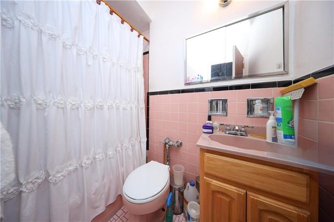 Bathroom featuring tile walls, vanity, a shower with shower curtain, and a wainscoted wall | Image 27