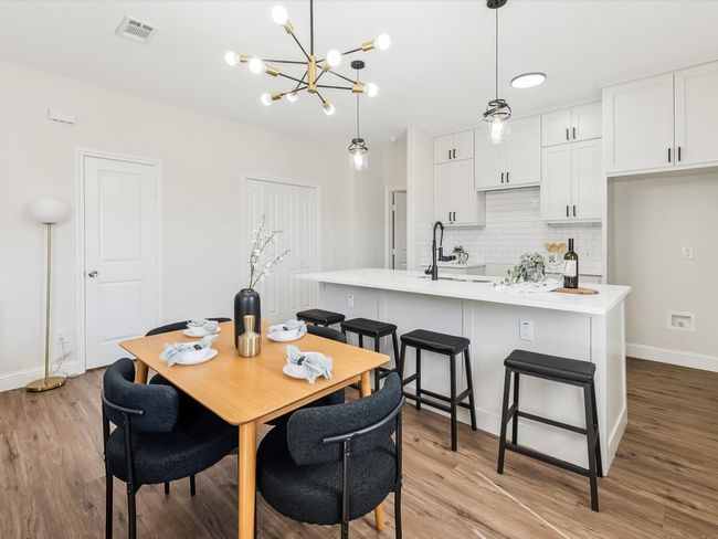 Dining space featuring visible vents, light wood finished floors, baseboards, and a notable chandelier | Image 7