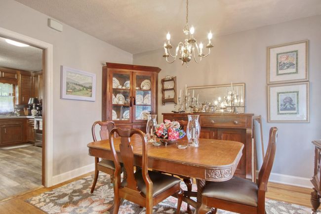 Dining room with light wood-style floors, a chandelier, and baseboards | Image 12
