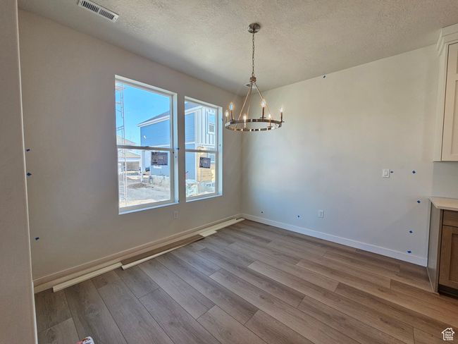 Unfurnished dining area featuring a chandelier, wood finished floors, and a textured ceiling | Image 12