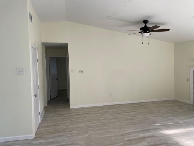 Unfurnished room with a ceiling fan, lofted ceiling, light wood-type flooring, and baseboards | Image 4