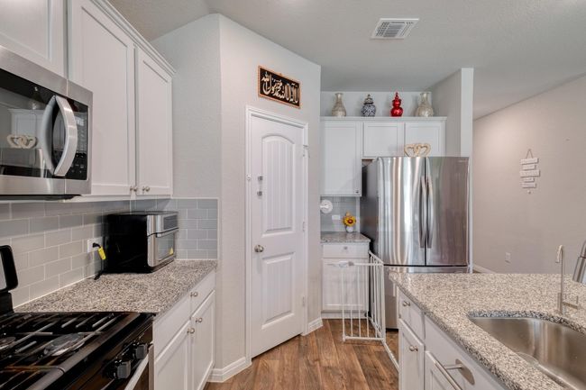 Kitchen with appliances with stainless steel finishes, a sink, white cabinetry, and backsplash | Image 14
